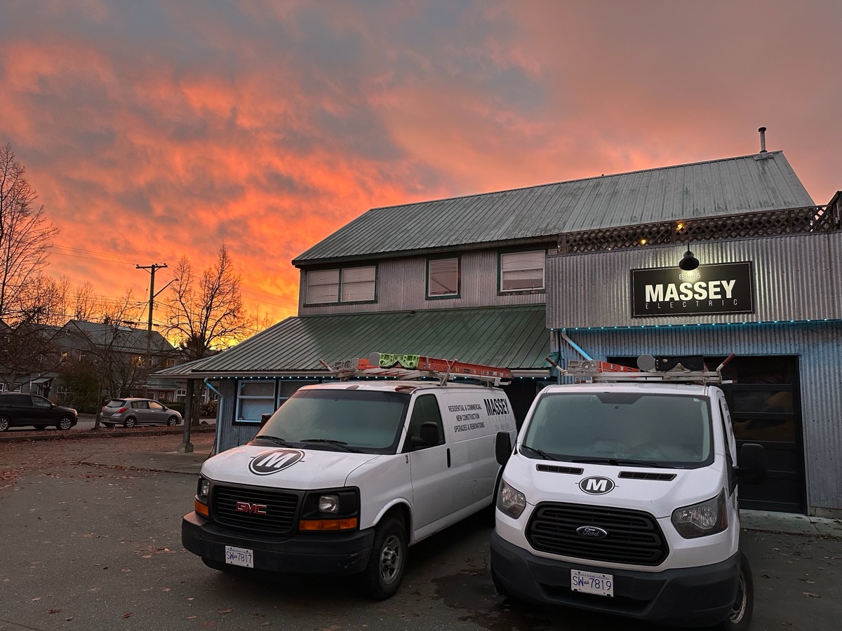 Massey Electric vans parked outside the Massey shop at sunset.
